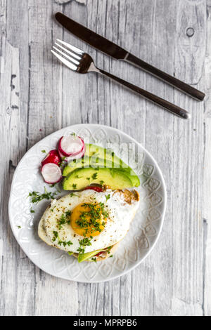 Toast mit mit Spiegelei, Avocado, rote Radieschen, Tomaten und Kresse Stockfoto