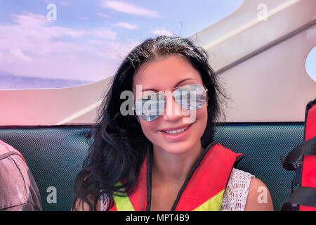 Lächelnd dunkelhaarige Frau Segel auf tropischen Meer Tragen von Schwimmwesten und Sonnenbrillen. Stockfoto