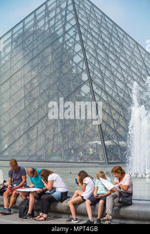 Eine Familie auf der Suche bei map durch die Pyramide des Louvre, Paris, Frankreich Stockfoto