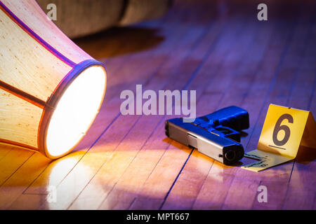 Eine Pistole ist mit ein Beweis Marker auf dem Fußboden eines Hauses gekennzeichnet. Ein Umgeworfen Lampe legt in der Nähe. Stockfoto