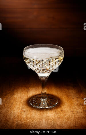 Spotlight auf einen Kristall Glas Champagner, Schuß auf einem antiken Holztisch. Stockfoto
