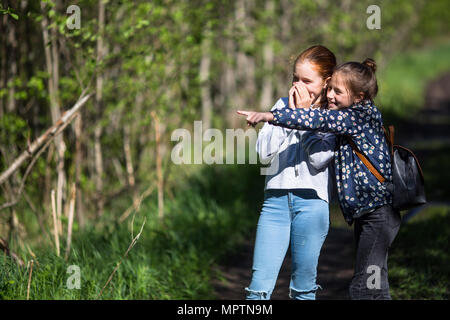 Freundin Punkte mit einem Finger irgendwo. Zwei Schwestern Spaß im Freien. Stockfoto