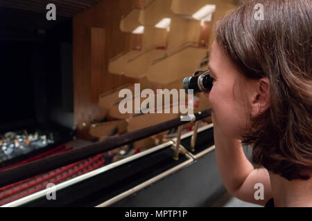 Eine Frau schaut dem Orchester in einem Theater mit operngläser Stockfoto