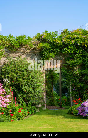 Britische Gärten. Einen schönen Sommer ummauerten Garten Grenze Blumenbeet Display inklusive verschiedenen Hortensien. Eine offene Tür zeigt einen Blick von einem ummauerten Gemüsegarten darüber hinaus. Stockfoto