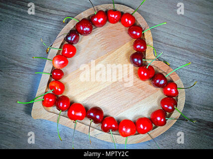 Sweet cherry Beeren im Herzförmigen hölzerne Schüssel in einer Reihe Stockfoto