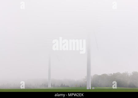 Zwei Windenergieanlagen vom Erie Ufer Wind Farm sind Gerste in low level Nebel an einem Frühlingstag im Südwesten von Ontario, Kanada sichtbar. Stockfoto