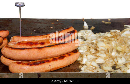 Große Hot Dog Würstchen grillen Neben gehackte Zwiebeln auf einem im BBQ-Grill. Thermometer in Fleisch. Street Hersteller Grill mit weißem Hintergrund Stockfoto