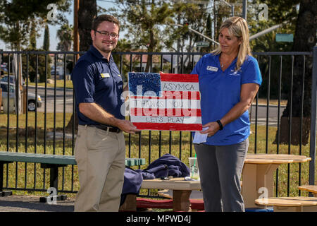 Samantha Holt, Recht, Programme Director für das Armed Services Young Men Christian Association (ASYMCA) Camp Pendleton, präsentiert ein Geschenk als ein Zeichen der Wertschätzung, Rob Reape, senior Einkäufer für Carmax Escondido, während eine "Woche der Play" Veranstaltung am Camp Pendleton, Kalifornien, 20. April 2017. ASYMCA, Fisher Kinderzentrum, erhielt ein Kaboom spielen Stipendium der CarMax Stiftung für militärische Kind Monat, wo ein Phantasie-Spielplatz offenbart wurde. (Foto: U.S. Marine Corps CPL. Brandon Martinez) Stockfoto