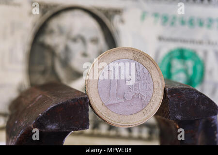 Finanzielle Dominanz: ein Euro in einen Schraubstock vor dem Hintergrund des amerikanischen Dollars mit Platz für Text Stockfoto