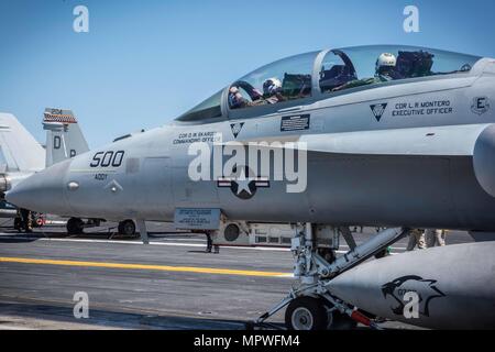 170419-N-MJ135-032 Pazifik (19. April 2017) Captain Craig Clapperton, Kommandierender Offizier der USS Theodore Roosevelt (CVN-71), fährt hinter Lt. CMdR William Blanton in eine EA - 18 G Growler zugewiesen, die Cougars der elektronischen Angriff Strike Squadron (VAQ) 139 auf dem Flugdeck der USS Theodore Roosevelt. Theodore Roosevelt führt im Gange des Schiffes eine maßgeschneiderte Ausbildung Verfügbarkeit vor der Küste von Kalifornien. (Foto: U.S. Navy Mass Communication Specialist 3. Klasse Spencer Roberts/freigegeben) Stockfoto