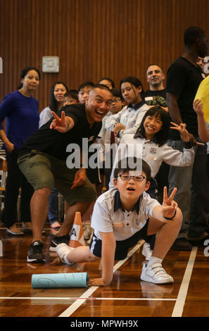 HONG KONG (10. April 2017) U.S. Navy Lt. CDR Aaron Carlton, Marine Kaplan mit USS Makin Island (LHD 8), posiert für ein Foto mit Kindern von Yan Chai Krankenhaus Recht Chan Chor Si Grundschule als Teil einer Gemeinschaft-Relations-Veranstaltung in Hongkong, April 10. Die Marines und Segler mit Makin Island amphibische bereit Group/11th Marine Expeditionary Unit meldete sich freiwillig zur Teilnahme an Team-building-Sport und erzählen über ihre Erfahrungen auf Schiff. Hong Kong ist eine der vielen Portbesuche, die USS Makin Island in den Westpazifik 16-2 Bereitstellung besucht. (U.S. Marine Corps Foto von Cpl. Ap Stockfoto