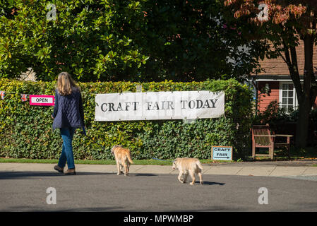 Eine Frau geht zwei Hunde Vergangenheit ein Banner mit Craft Fair heute in der Nähe von Arundel in West Sussex, UK. Stockfoto