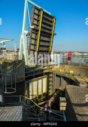 Eine Brücke über die Bucht von Cardiff Barrage in der angehobenen Position mit dem Gatter Mechanismus im Vordergrund. Eine Person steht auf der Seite betrachtet. Stockfoto