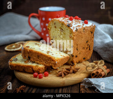 Gebackene großen Kuchen mit getrockneten Früchten und in Scheiben schneiden auf einem Holzbrett, braun Tabelle Stockfoto