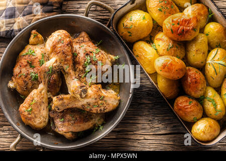 Gebratene Hähnchenschenkel mit Kartoffeln Kümmel Pfeffer und Kräutern oben auf Ansicht. Stockfoto