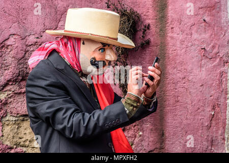 Cuidad Vieja,, Guatemala - Dezember 7, 2017: Maskierte lokale in Parade feiern, Unserer Lieben Frau von der Unbefleckten Empfängnis Tag schaut am Handy Stockfoto