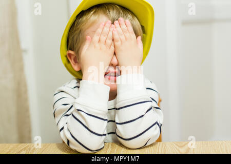 Verspielter Junge, die Augen mit den Händen, während zu Hause spielen Stockfoto