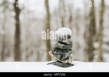 Stapel von Steinen auf Schnee im Wald Stockfoto
