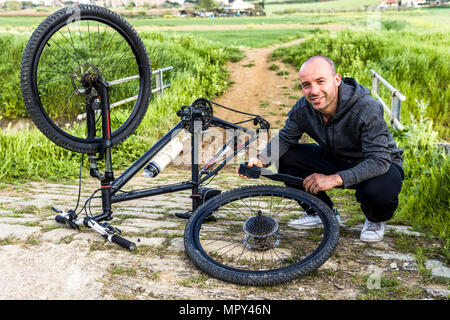 Porträt des Menschen Reparatur Fahrrad auf Feld gegen Farm Stockfoto