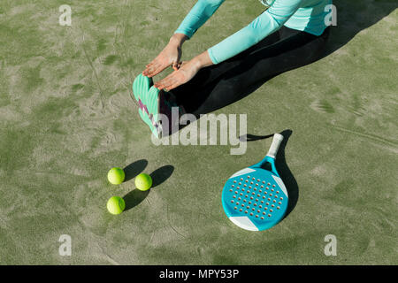 Niedrige Abschnitt von Frau stretching mit Tennisschläger und Bälle auf Gericht während der sonnigen Tag Stockfoto