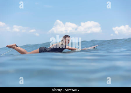 Volle Länge Portrait von sorglosen lächelnde Frau liegend auf Surfbrett, beim Schwimmen im Meer Stockfoto