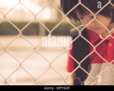 Vintage Style der traurige junge hinter Zaun Gitter Verrechnung. Emotionen Konzept - Traurigkeit, Trauer, Melancholie. Stockfoto