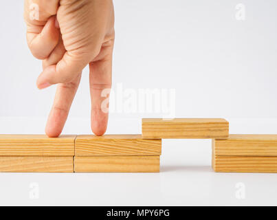 Closeup Hand klettern Holzblock Treppen auf weißem Hintergrund. Konzept der Gebäude erfolg Stiftung. Stockfoto