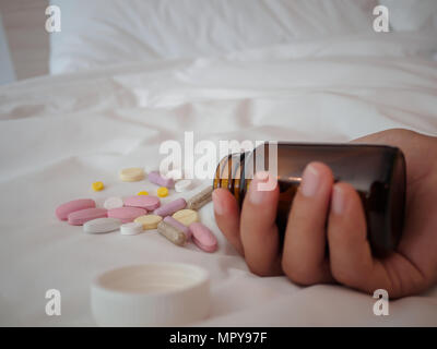 Closeup Frau Hand auf dem Bett liegend mit Pillen. Drogen überdosis oder Selbstmord Konzept. Stockfoto