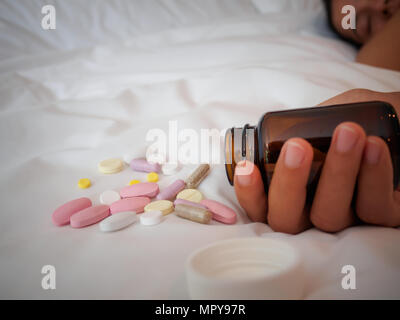 Closeup Frau Hand auf dem Bett liegend mit Pillen. Drogen überdosis oder Selbstmord Konzept. Stockfoto