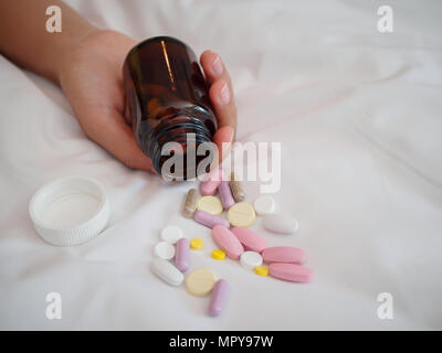 Closeup Frau Hand auf dem Bett liegend mit Pillen. Drogen überdosis oder Selbstmord Konzept. Stockfoto