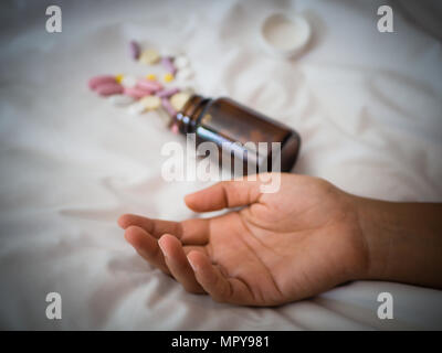 Closeup Frau Hand auf dem Bett liegend mit Pillen. Drogen überdosis oder Selbstmord Konzept. Stockfoto