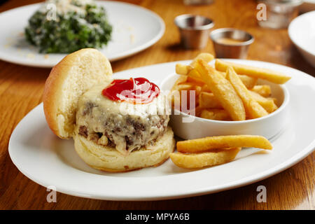 In der Nähe von Cheeseburger mit Pommes frites in der Platte auf hölzernen Tisch serviert Stockfoto