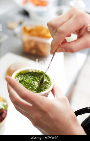 7/8 Hand der Frau, Pesto in der Küche Stockfoto