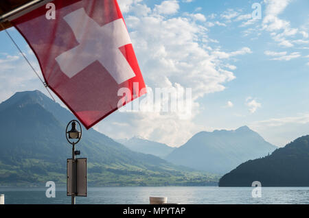 Schweizer Flagge aus Fokus in Rahmen mit Fokus auf die Berge im Hintergrund Stockfoto