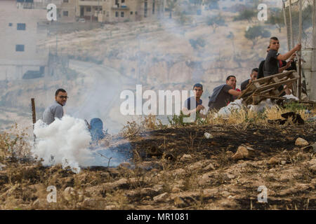 Bethlehem, West Bank Stadt Bethlehem. 25 Mai, 2018. Die Palästinenser, die Israel versucht, das umstrittene Schranke in Jerusalem aus der West Bank zu überqueren, um zu klettern und wurden durch israelische Sicherheitskräfte verboten, um die Abdeckung vom Gas von israelischen Sicherheitskräften feuerte Tränengas zu nehmen, da sie den Weg der zweite Freitag des Ramadan Gebet in Jerusalem's al-Aqsa Moschee zu besuchen, in der Nähe der West Bank Stadt Bethlehem, am 25. Mai 2018. Credit: luay Sababa/Xinhua/Alamy leben Nachrichten Stockfoto