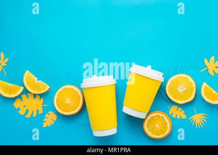 Pappbecher mit Zitronenscheiben und tropische Blätter auf einem blauen Hintergrund. Sommer trinken zu gehen mit Kopie Raum legen. Limonade von oben Stockfoto