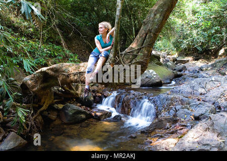 Müde Frau sitzt auf einem Baumstamm. Die Natur von Asien. Stockfoto