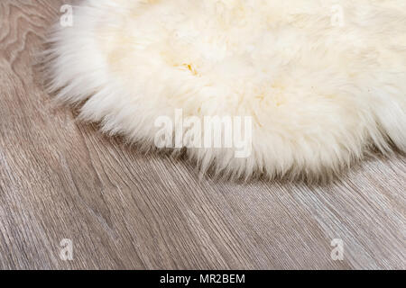 Dekorative Fell Teppich auf Parkett Hintergrund. Weiße Haut auf dem Parkett in der Wohnung. Matte aus natürlichen Haut von Kaninchen. Stockfoto