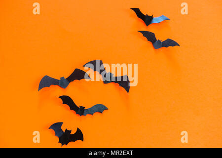 Schwarzes Papier Fledermäuse fliegen auf orangem Hintergrund. Halloween Dekoration Konzept. Stockfoto