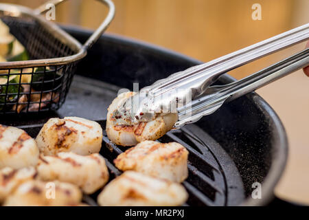 Köstliche sizzling Jakobsmuscheln Grillen auf einem Holzkohlegrill Stockfoto