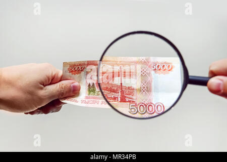 Experte mit Lupe überprüft verdächtige Geld. suche Wasserzeichen auf Papier der gefälschten Rechnungen. Lupe, Lupe, Lupe, magn Stockfoto