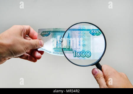 Experte mit Lupe überprüft verdächtige Geld. suche Wasserzeichen auf Papier der gefälschten Rechnungen. Lupe, Lupe, Lupe, magn Stockfoto
