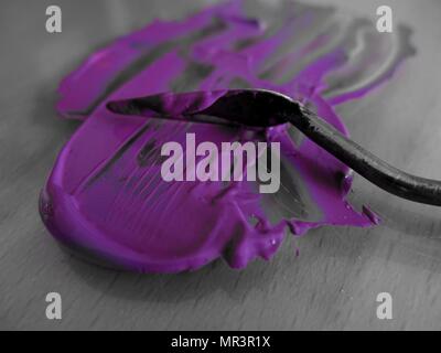 Spachtel zum Mischen violetter Acrylfarbe. Konzept: Malen, kreativ sein. Stockfoto