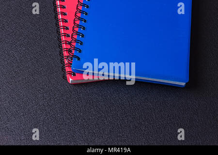 Verschiedene mehrfarbige Notebooks auf eine Spirale auf schwarzem Hintergrund Stockfoto