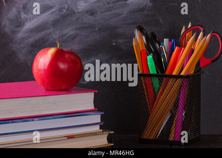 Schule Bücher mit Apple auf dem Schreibtisch, auf dem Schwarzen Brett Hintergrund Stockfoto