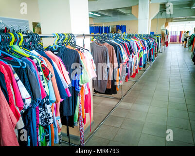 Viele verschiedene Klamotten auf Bügeln hängend im Store. Stockfoto