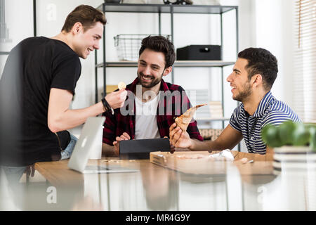 Lächelnd Freunde essen Pizza und das Sprechen über digitale cryptocurrency Stockfoto