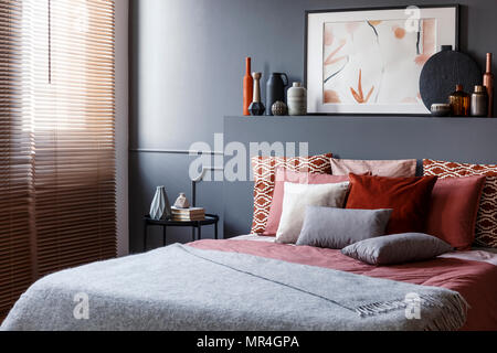 Kissen auf einem Doppelbett neben einem Nachtschrank, Dekorationen und Malerei oben in einem Schlafzimmer Innenraum Stockfoto