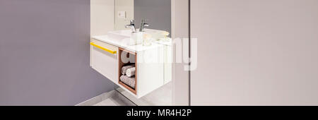 Seitenansicht der modernen Waschbecken mit einem Schrank und Handtücher neben einem leeren Wand im Bad Stockfoto