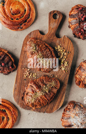 Flach mit frisch gebackenem süßen Croissants mit Pistazien auf Holz Schneidebrett auf helle Oberfläche Stockfoto